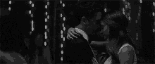 a black and white photo of a man and a woman kissing .