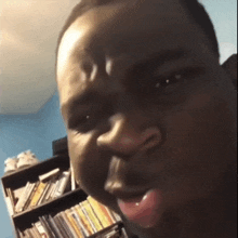 a close up of a man 's face in front of a bookshelf