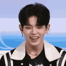 a young man wearing a black and white jacket is smiling .