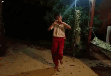 a boy in red pants and a white shirt is praying in the dark