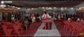 a man is walking down a red carpet in front of a crowd of people in a room .