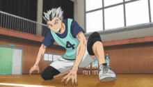 a man is kneeling down on the floor in a basketball court .
