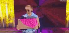 a man is holding a box with a pink cloth on top of it .