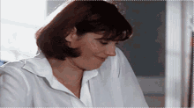 a woman wearing a white shirt is smiling with her eyes closed