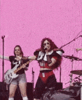 a woman is singing into a microphone while holding a guitar .