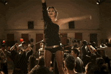 a woman in a black top is dancing in front of a crowd of people