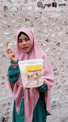 a woman in a pink hijab is holding a container of renftinans