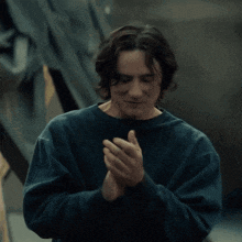 a man in a blue sweatshirt is clapping his hands together