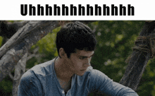 a man in a blue shirt sits in front of a tree with the words uhh on the top