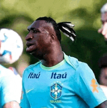 a soccer player with dreadlocks is wearing a blue shirt with itau written on it .