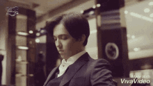 a man in a suit is sitting in front of a gucci sign