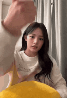 a girl wearing a white shirt that says ' always ' on it is sitting on a yellow pillow