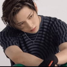 a man wearing a striped shirt and a necklace is looking down
