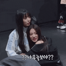 two girls are hugging each other in a dark room with a question mark in the middle