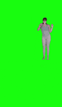a woman in a tank top and white pants is dancing on a green screen