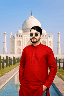 a man in a red shirt and sunglasses stands in front of a white building