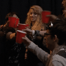 a group of people are holding up red cups in a toast