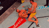 two men are fighting in a boxing ring with a budweiser ad on the floor