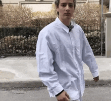 a young man wearing a white shirt with a button down collar is walking down the street