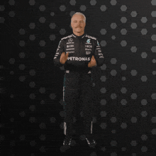 a man in a petronas uniform is clapping his hands in the air