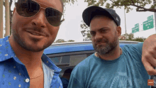 two men are posing for a picture in front of a street sign that says greenway