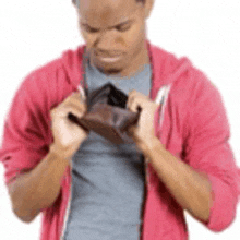 a man in a pink hoodie is holding an empty wallet .
