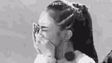 a black and white photo of a woman covering her mouth .