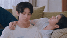two young men are laying on a couch with one wearing a shirt that says floral sunshine