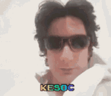 a man wearing sunglasses and a white shirt says kesoc on the bottom