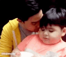 a man in a yellow hoodie kisses a little girl on the cheek