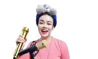 a woman in a pink shirt is singing into a microphone with a stuffed animal on her head