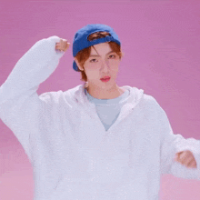 a person wearing a blue hat and a white shirt making a heart with their hands