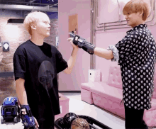 a man wearing a black shirt that says ' everybody ' on it stands next to another man