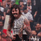 a man wearing a skeleton shirt is holding a championship belt and has tiffany luv24 written on the bottom right