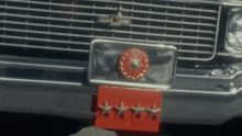 the front of a silver chevy with a red license plate that has four stars on it