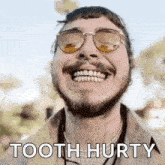 a man with a beard and sunglasses is smiling and saying tooth hurty .