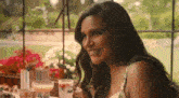 a woman is smiling while sitting at a table with a drink .