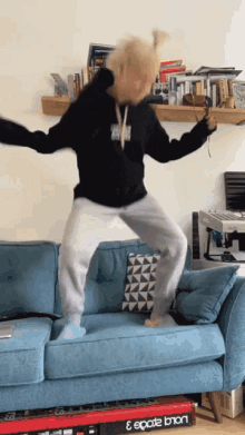 a person is jumping on a blue couch next to a keyboard that says ecode bton