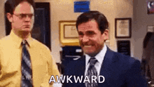 a man in a suit and tie is making a funny face while standing next to another man in a yellow shirt .