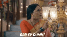a woman in a red and gold sari is pointing at something and says bas ek dum