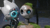 two robots are standing next to each other on a rock with moss on it