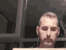 a man with a beard is sitting in front of a laptop computer wearing headphones .