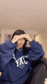 a woman wearing a blue sweatshirt that says yku on it