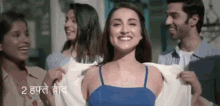 a group of people are standing around a woman in a blue tank top and smiling .