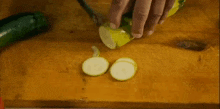 a person is cutting a zucchini on a cutting board with a knife .