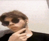 a man wearing sunglasses and a black shirt is taking a selfie .