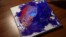 a painting of a blue and red circle on a white canvas