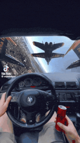 a person driving a car with a can of soda in front of them