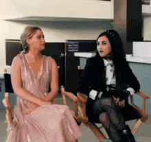 two women are sitting in chairs talking to each other