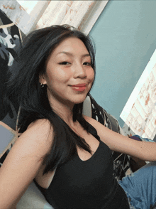 a woman in a black tank top is laying on a bed